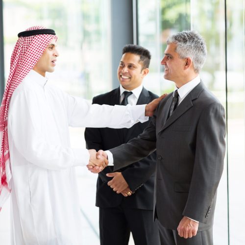 multicultural business partners handshaking in office